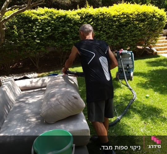 אדם מנקה ספה עם מכונת ניקוי חיצונית